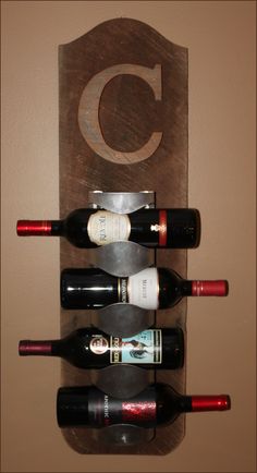 a wine rack with six bottles on it and the letter c hanging from the wall