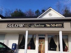 the front of a salon with white siding and windows