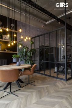 an office with wood flooring and plants hanging from the ceiling, surrounded by glass walls