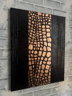 a black and gold painting on a brick wall with white bricks in the back ground