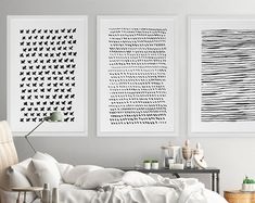 three black and white paintings hang on the wall above a bed