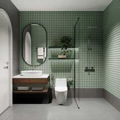 a green tiled bathroom with a toilet, sink and mirror