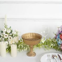 a table topped with flowers and candles next to a vase filled with white roses on top of a table