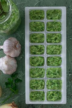 an ice tray filled with guacamole and garlic on top of a table