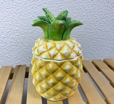 a yellow pineapple shaped vase sitting on top of a wooden table