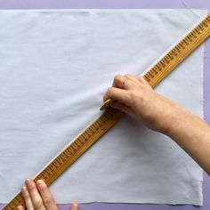 someone is measuring the length of a piece of paper with a ruler on top of it