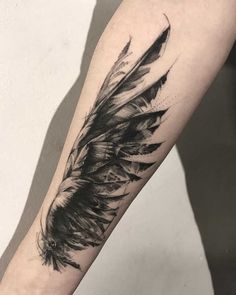 a black and white feather tattoo on the arm