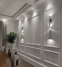 an elegant dining room with white walls and wood floors, along with modern lighting fixtures