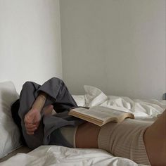 a woman laying in bed with her legs crossed and reading a book while wearing knee high socks