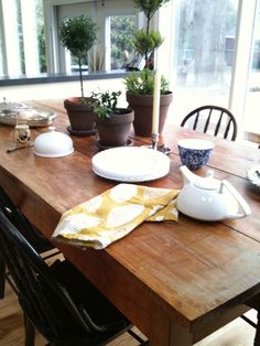 a wooden table topped with plates and potted plants