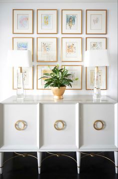 a white sideboard with four drawers and a potted plant in front of it