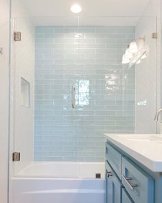 a bathroom with blue and white tiles on the shower wall, sink and bathtub