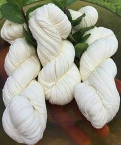 several skeins of yarn sitting on top of a glass bowl in the grass