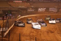 several cars are racing on the dirt track