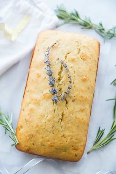 a loaf of bread with lavender sprigs on it sitting on top of a table