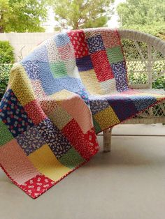 a patchwork quilt sitting on top of a white bench