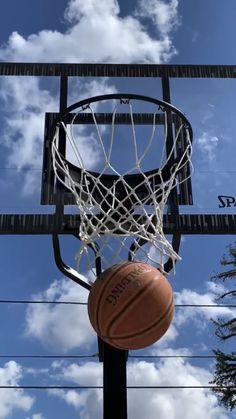 a basketball is going through the hoop in front of some power lines and clouds on a sunny day