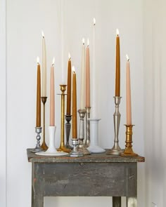 a bunch of candles are lined up on top of an old table with other items