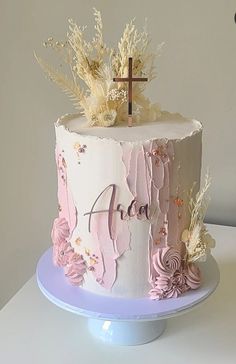 a white cake with pink flowers and a cross on top