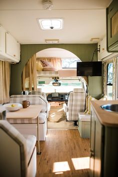 the interior of an rv with wood flooring and white couches in front of it