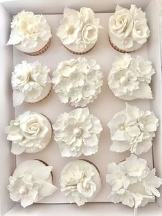 cupcakes decorated with white flowers in a box