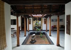 the inside of a house with columns and a water feature in the center surrounded by plants