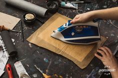 a person ironing something on top of a piece of paper next to other tools