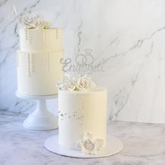 two white wedding cakes sitting next to each other on top of a marble countertop