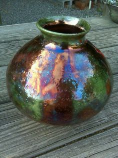 a green vase sitting on top of a wooden table