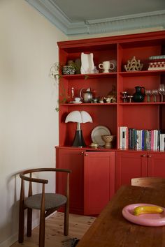 a red bookcase in the corner of a dining room