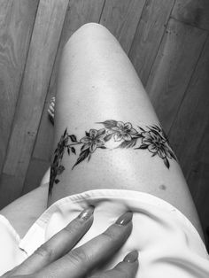 a woman's leg with flowers on it and her hand resting on the ground