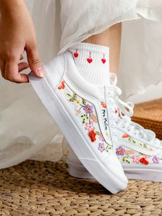 a person wearing white shoes with flowers on them