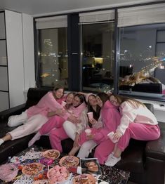 a group of women sitting on top of a couch in front of a table filled with donuts