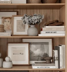 books, vases and pictures are on the shelves