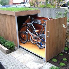 two bikes are parked in an outdoor storage area with grass growing on top of the roof