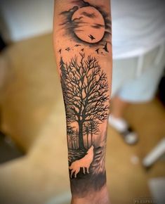 a person with a tattoo on their arm that has a wolf and tree in the background