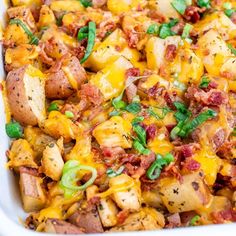 a casserole dish filled with potatoes, bacon and green onions in a white baking dish