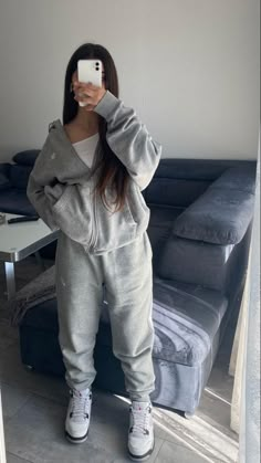 a woman taking a selfie in front of a couch with her cell phone up to her ear