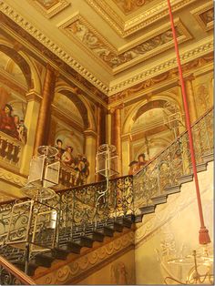 an ornate staircase with paintings on the walls