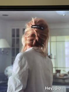 a woman with red hair in a white shirt is looking at something on the television screen