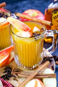 two mugs filled with apple cider and cinnamon sticks