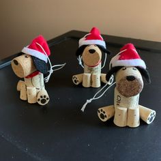 three wooden dogs wearing santa hats on top of a black table next to each other