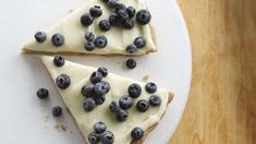 two slices of blueberry cheesecake on a white plate with fresh blueberries scattered around them