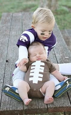 two babies playing with a football on a picnic table