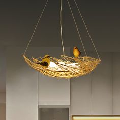 three birds sitting on top of a bird nest suspended from a ceiling fixture in an office