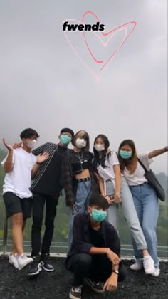 group of people wearing face masks standing on top of a hill