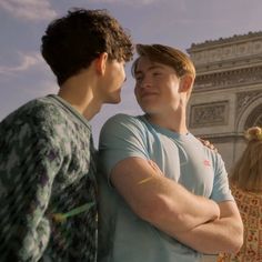 two young men standing next to each other in front of a building with an arch