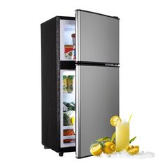 a silver refrigerator with its door open next to lemons and a glass of orange juice