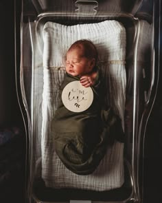 a baby is sleeping in a clear crib with a sign on it's side