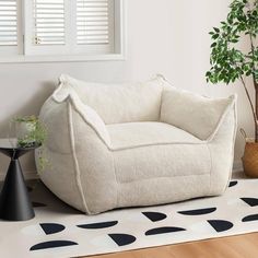 a white chair sitting on top of a wooden floor next to a potted plant